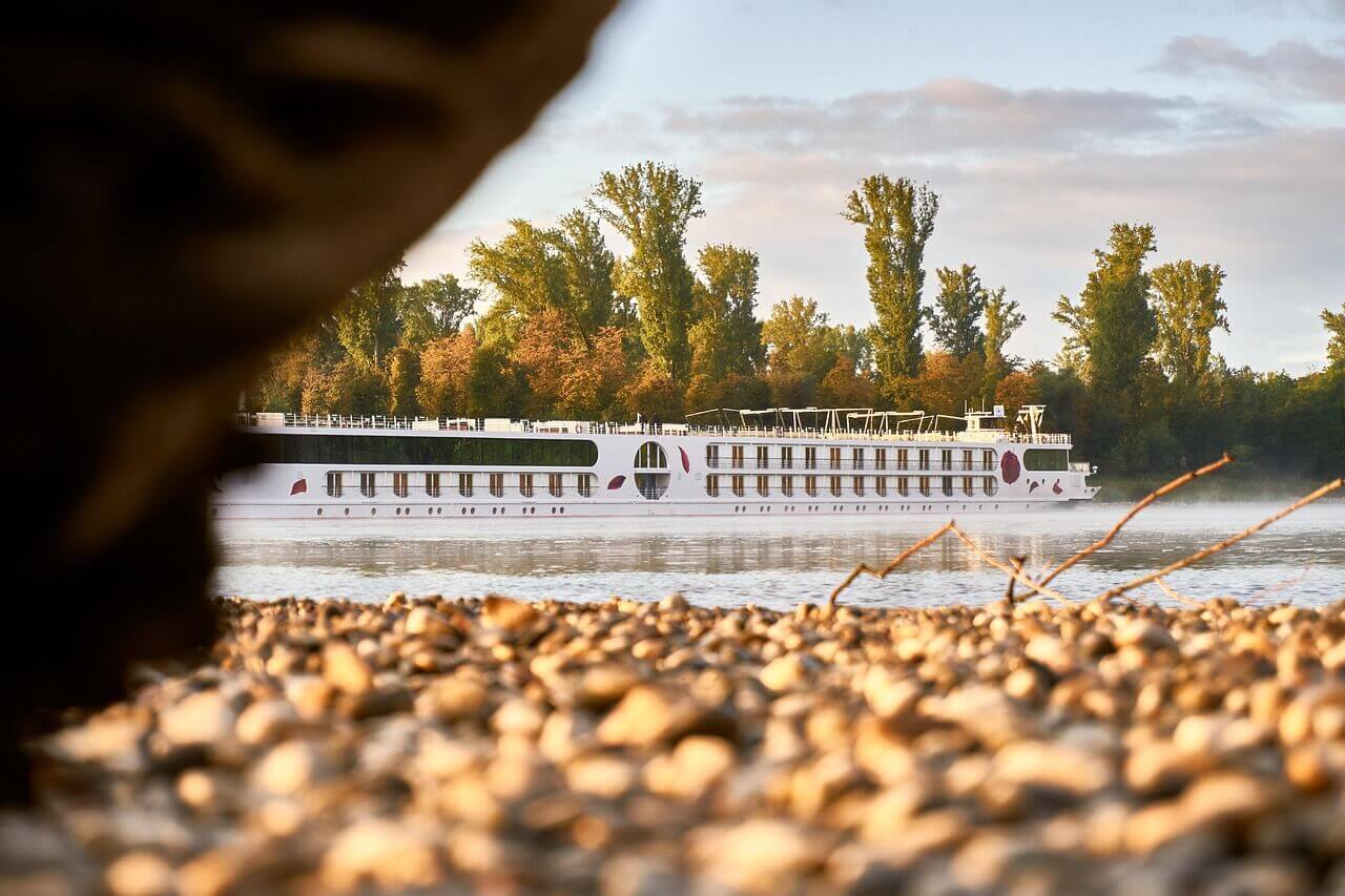 A serene Rhine River cruise ship sailing under a golden sunset, capturing the essence of a tranquil river journey.